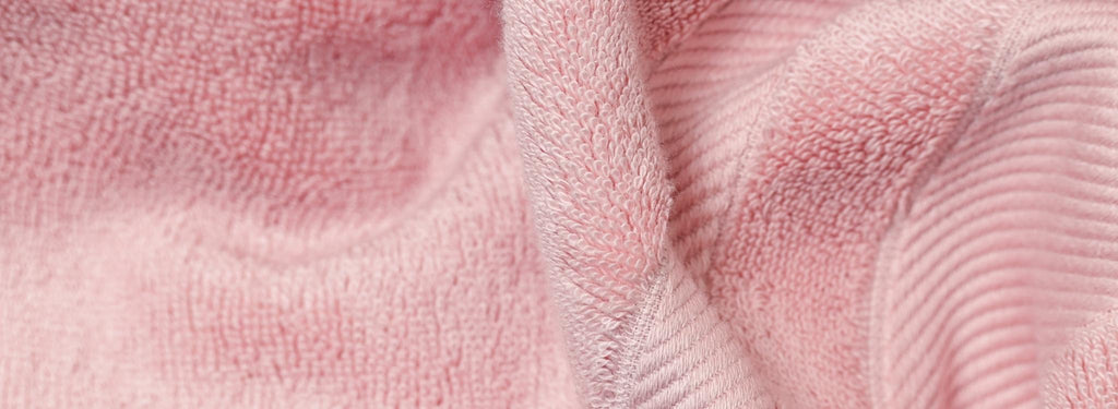 close up shot of folded dusk pink bath towel showing looped pile containing TENCEL™ Lyocell 